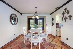 A dining area with a round table and white chairs, a decorative mirror, and a view of the garden through a door. - 2 Bedroom 2 bath (Sarasota)