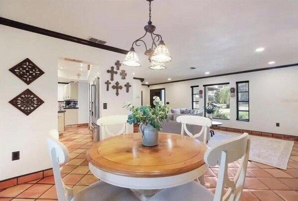 A dining area with a round wooden table, white chairs, and a hanging light fixture. - 2 Bedroom 2 bath (Sarasota)