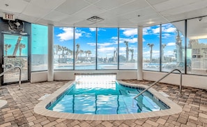 Piscina interior con vistas claras a palmeras y al área de la piscina exterior.