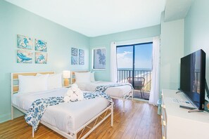 Ein Hotelzimmer mit zwei Betten, einem Fernseher, einem Balkon mit Blick und Kunstwerken an den Wänden.