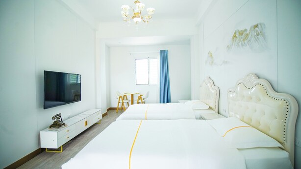 Une chambre d’hôtel moderne avec un grand lit, une télévision, une petite table avec des chaises et un lustre.