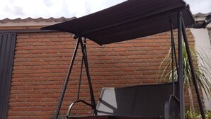 En uteplats med en gungstol och en grill.