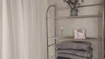 Een douche, handdoeken, zeep, toiletpapier