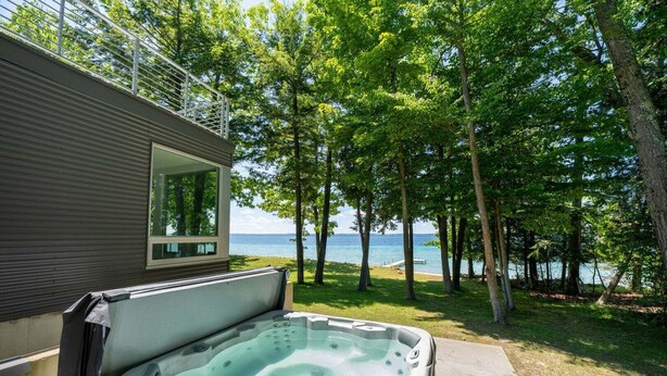 A hot tub in a backyard with a view of the lake and trees. - Old Mission Peninsula Luxury on West Bay (Traverse City)