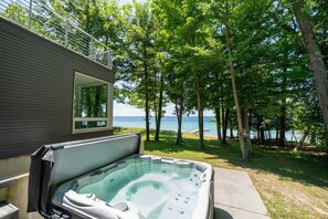 A hot tub in a backyard with a view of the lake and trees.