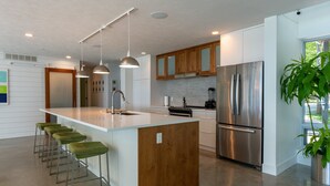 A modern kitchen with a central island, stainless steel appliances, and green bar stools. - Old Mission Peninsula Luxury on West Bay (Traverse City)