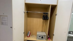 A walk-in closet with wooden shelves, a microwave, and a red iron.