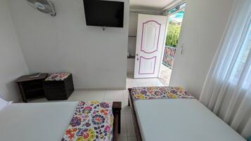Habitación con dos camas, televisión, escritorio y puerta que da a un espacio exterior.