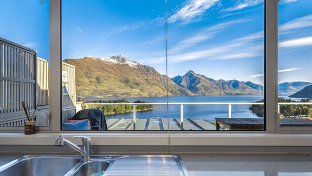 A kitchen with a large window overlooking a lake and mountains. - Panorama Terrace: Lake Views, Deck & Walk to Town (Queenstown)