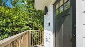 A wooden deck with a black door and a mailbox on the side of a house.