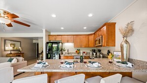 A modern kitchen with wooden cabinets, a granite countertop, and a central island with bar seating.