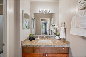 A bathroom with a granite countertop, a sink, a mirror, and a towel rack. - 2bd tropical, walk to beach stay (Honokowai)