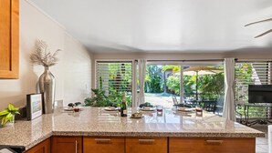 A kitchen with a granite countertop, wooden cabinets, and a view of a patio with outdoor furniture.