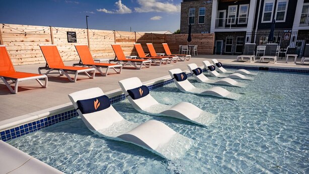 A pool area with lounge chairs and a wooden wall. - Relaxing 1 BR Retreat w Resort Amenities  (Waukee)