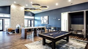 A modern living room with a pool table, bar area, and seating. - Relaxing 1 BR Retreat w Resort Amenities  (Waukee)