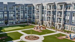 A modern apartment complex with a central courtyard, outdoor seating area, and a well-maintained lawn. - Relaxing 1 BR Retreat w Resort Amenities  (Waukee)