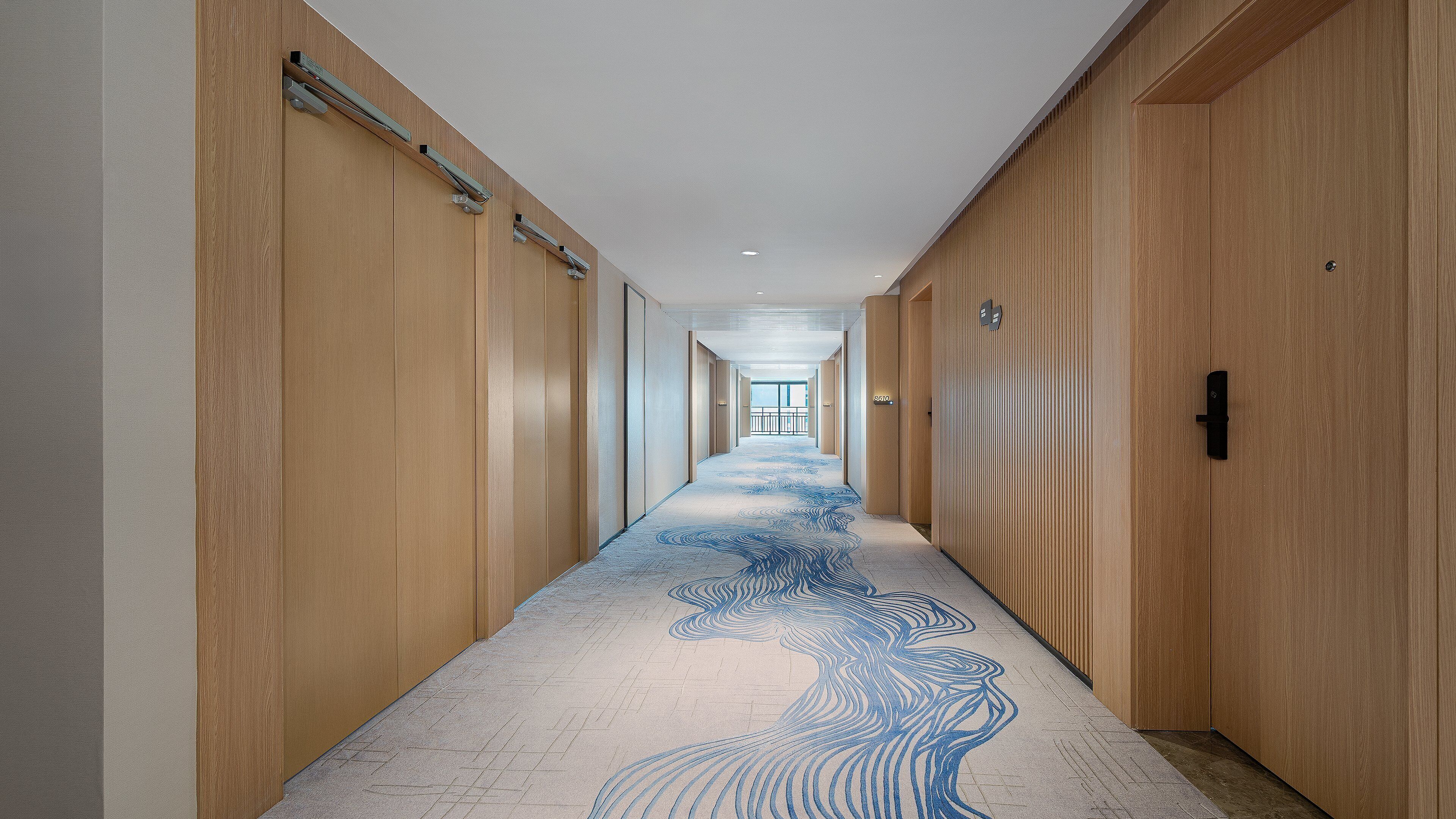 A long, narrow hallway with wooden paneling on the walls and a patterned carpet.