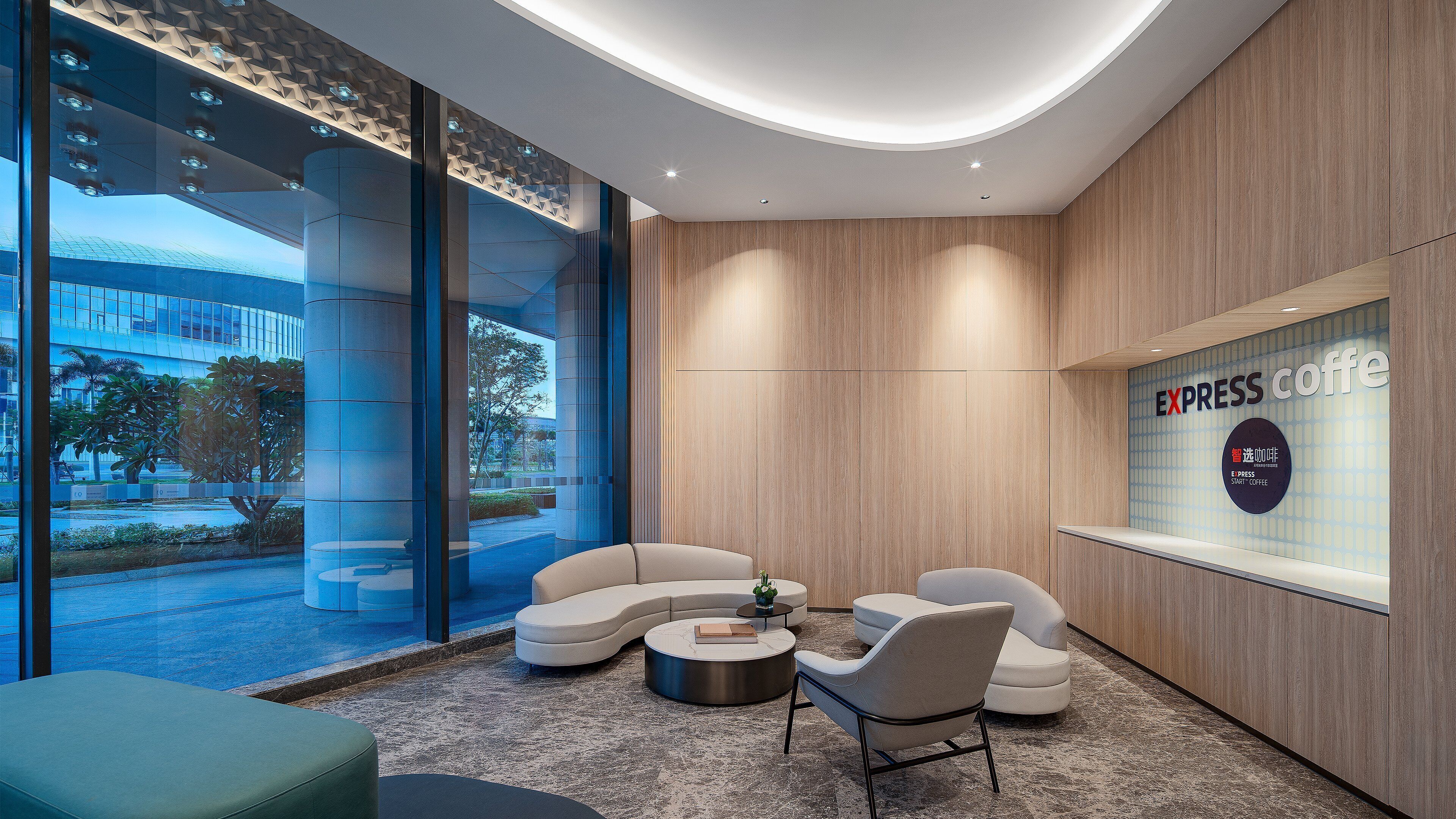 A modern lounge area with a seating arrangement, a coffee station, and a view of the outside.