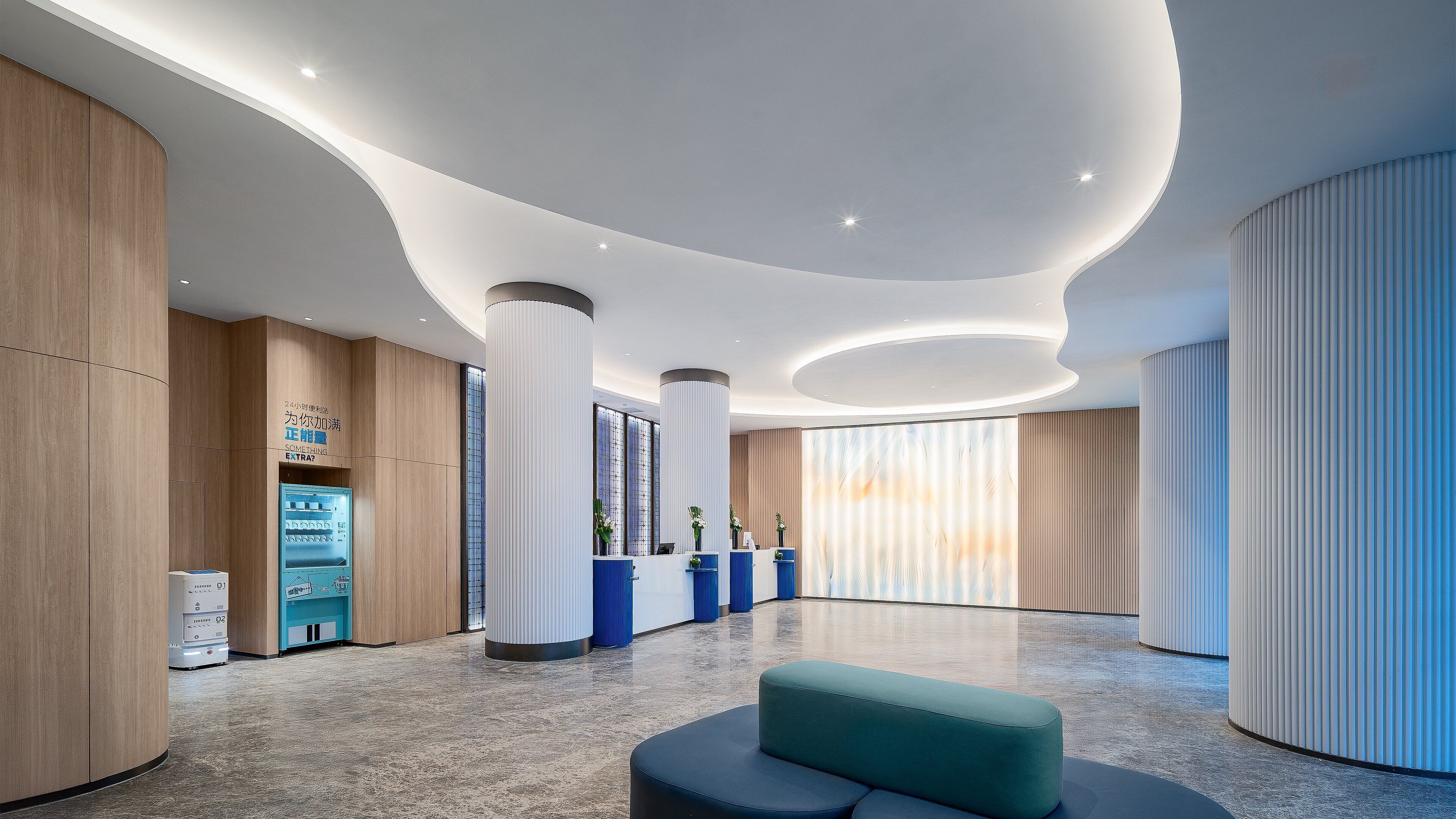 A modern lobby with a reception desk, seating area, and a large window.