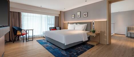 Ein modernes Hotelzimmer mit einem großen Bett, einem Schreibtisch mit Stuhl, einem kleinen Tisch und einer Couch.