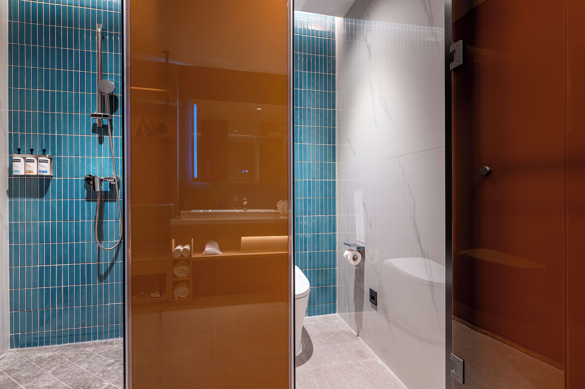 A modern bathroom with a glass shower enclosure, a white toilet, and a sink with a mirror.
