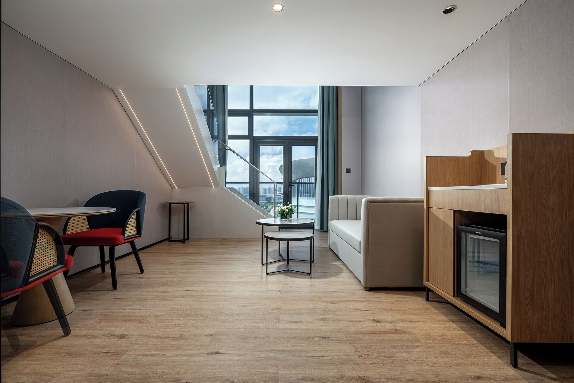 Una sala de estar moderna con comedor, un sofá y una cocina con horno empotrado.