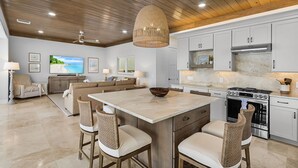 A modern kitchen with a large island, white cabinetry, and a built-in oven. - 319 Bay and Beach Blessing: Bay Front Pool Home w/ Gulf Views (Fort Myers Beach)