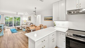 Una cocina moderna con armarios blancos, una isla grande y una campana de acero inoxidable.