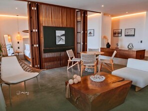 Ein modernes Wohnzimmer mit einer Holzwand, einem runden Tisch, weißen Sofas und einem an der Wand befestigten Fernseher.