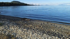 A rocky shoreline with calm water and a distant hill. - Pukawa Villas (Formerly Oreti Village Resort) (Pukawa)