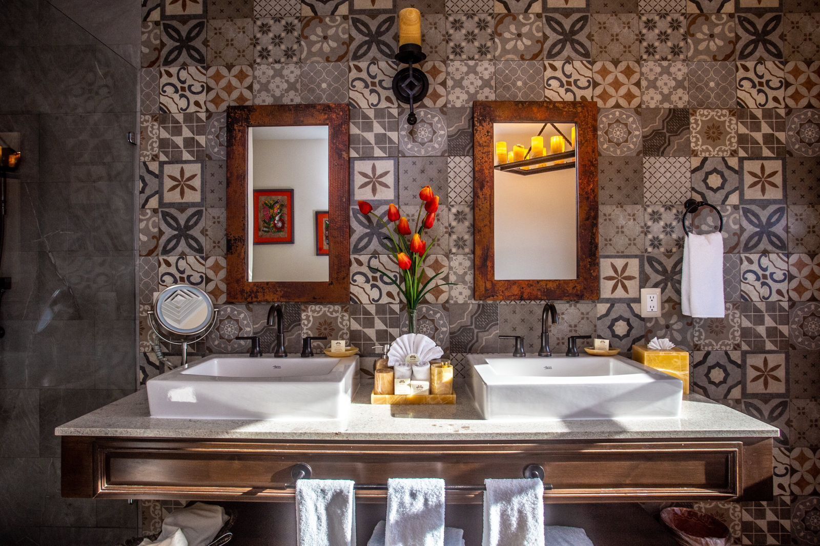 Ein Badezimmer mit zwei Waschbecken, einem Spiegel, einer Blumenvase und einem Handtuchhalter.