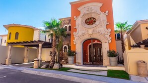 A Mediterranean-style building with a central archway, palm trees, and a clear sky.