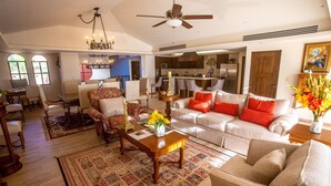 A spacious living room with a sofa, armchairs, a coffee table, and a chandelier.