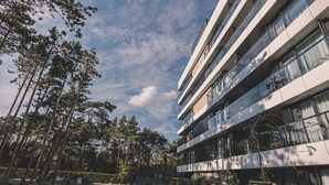 Ein modernes Gebäude mit mehreren Stockwerken, großen Fenstern und einem Weg zum Eingang.