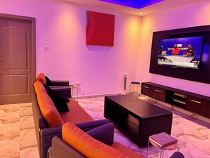 A modern living room with a large flat-screen TV, a sofa, a coffee table, and a cabinet. - ESPADA LODGE Studio 3.3 (Somanya)