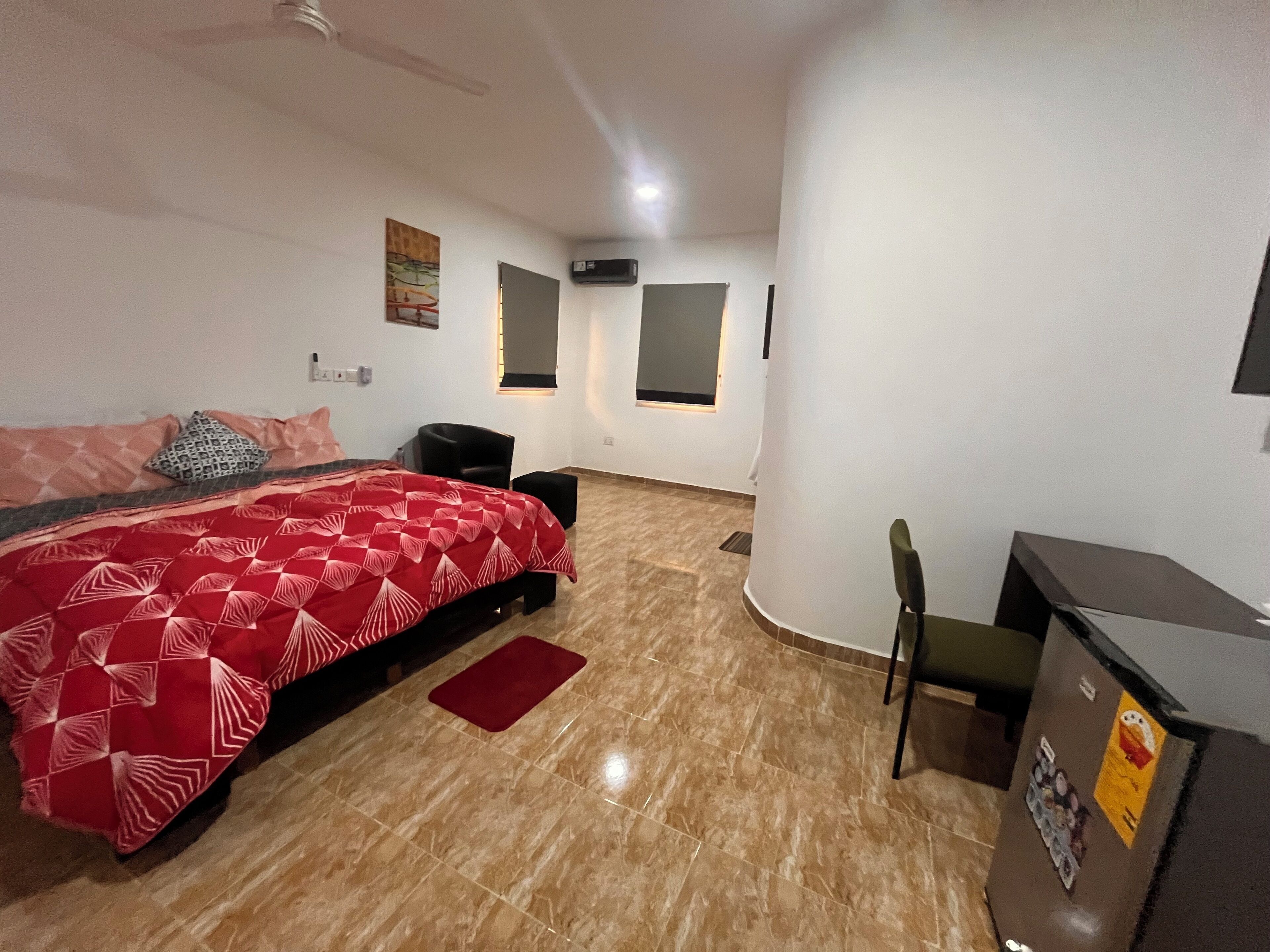 A bedroom with a bed, a desk, a chair, a heater, and a wall-mounted air conditioner.