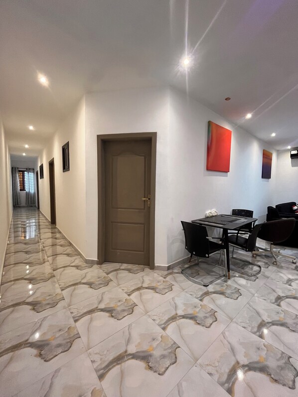 A hallway with a marble floor, a closed door, and a table with chairs. - ESPADA LODGE Studio 3.3 (Somanya)