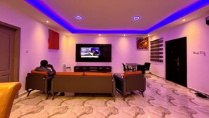 A modern living room with a flat-screen TV, comfortable seating, and a decorative wall piece. - ESPADA LODGE Studio 3.3 (Somanya)