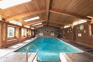 Una piscina interior con paredes de madera y una pared de piedra al fondo.