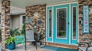 A building entrance with a brick facade, a teal-colored door, and a welcome sign.