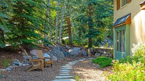 A garden with a wooden path, two Adirondack chairs, and a stone wall. - Exclusive Cascade Home - Close to Cascade Lift (Vail)