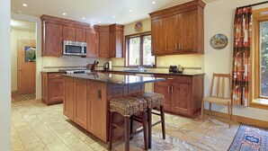 A spacious kitchen with wooden cabinets, a central island, and a large window providing natural light. - Exclusive Cascade Home - Close to Cascade Lift (Vail)
