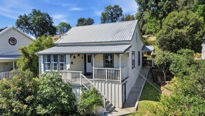Ein zweistöckiges Haus mit Veranda, sichtbarer Treppe und umzäunter Garten.