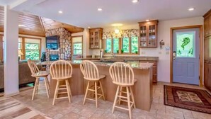 Una cocina moderna con un muro de acento de piedra, taburetes de bar de madera y una isla grande.