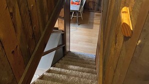 A wooden interior with a staircase leading to a dining area.