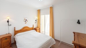 A bedroom with a wooden bed, bedside tables, a lamp, and a view of the outdoors. - Apartamentos Solset Nerja B (Nerja)