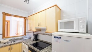 A compact kitchen with a microwave, sink, and a washing machine. - Apartamentos Solset Nerja B (Nerja)