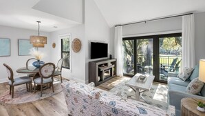 Una sala de estar moderna con chimenea, televisión y comedor con sillas y mesa.