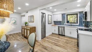 Una cocina moderna con armarios blancos, un refrigerador de acero inoxidable y un backsplash de azulejos azules.