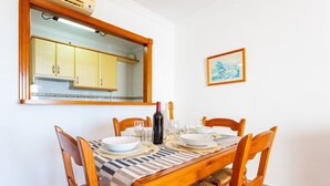 A dining table set for four with wooden chairs, a striped tablecloth, and a wine bottle. - Apartamentos Solset Nerja A (Nerja)